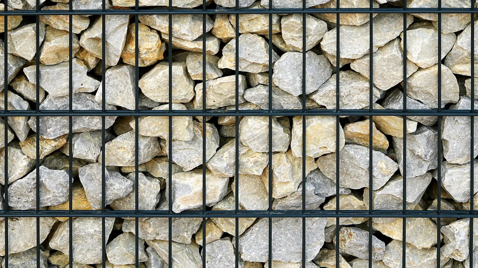 Tan stacked-stone retaining wall with planted desert specimens above.